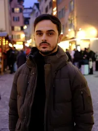 Frederik Lekaj, Teilnehmer des Young Talents-Programms, steht in einer belebten Fußgängerzone mit beleuchteten Geschäften im Hintergrund.