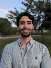 JOÃO ANDRÉ GOMES MARQUES, Teilnehmer des Young Talent Programms, des cyberintelligence institute. Er steht in einem Park und lächelt freundlich.